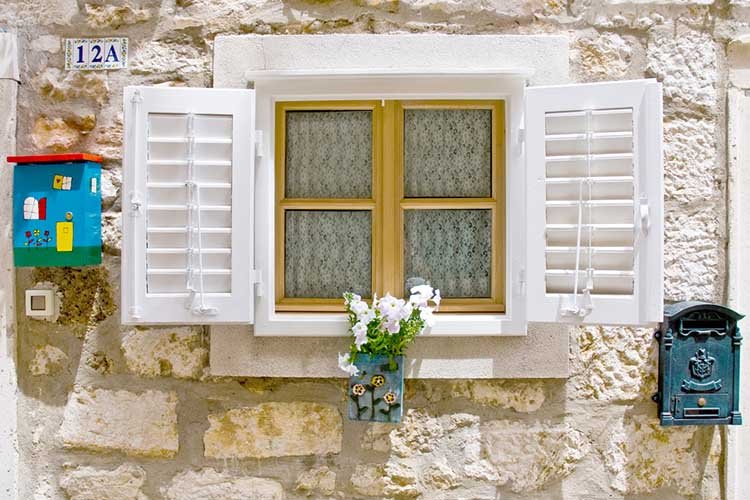 Old styled European window with shutters, flower box and mail box